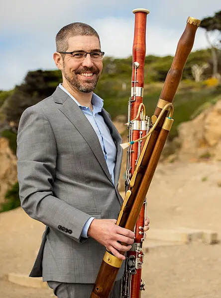 David Wells holding a modern bassoon and a Baroque bassoon